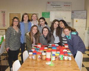 Students from the Friends' Central's Service Committee holding bottles of peanut butter at the Philabundance Hunger Relief Center