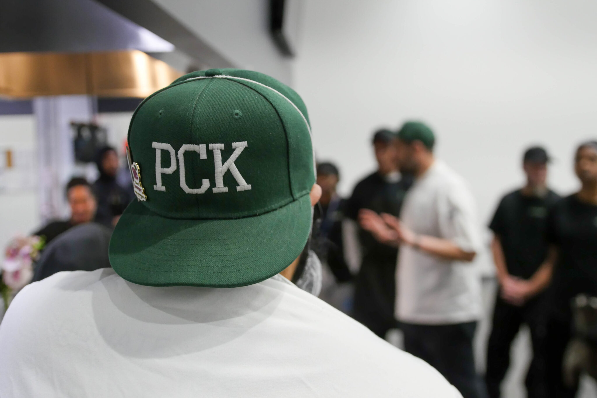 The back of a PCK chef wearing a forest green hat with PCK stitched onto the hat in white